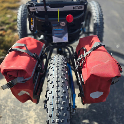 Closeup view of the panniers and rear tire on the ICE Full Fat RS Rohloff Shimano EP8 Hostel Shoppe Limited Edition Custom Blue Recumbent Trike outside in front of the Hostel Shoppe.
