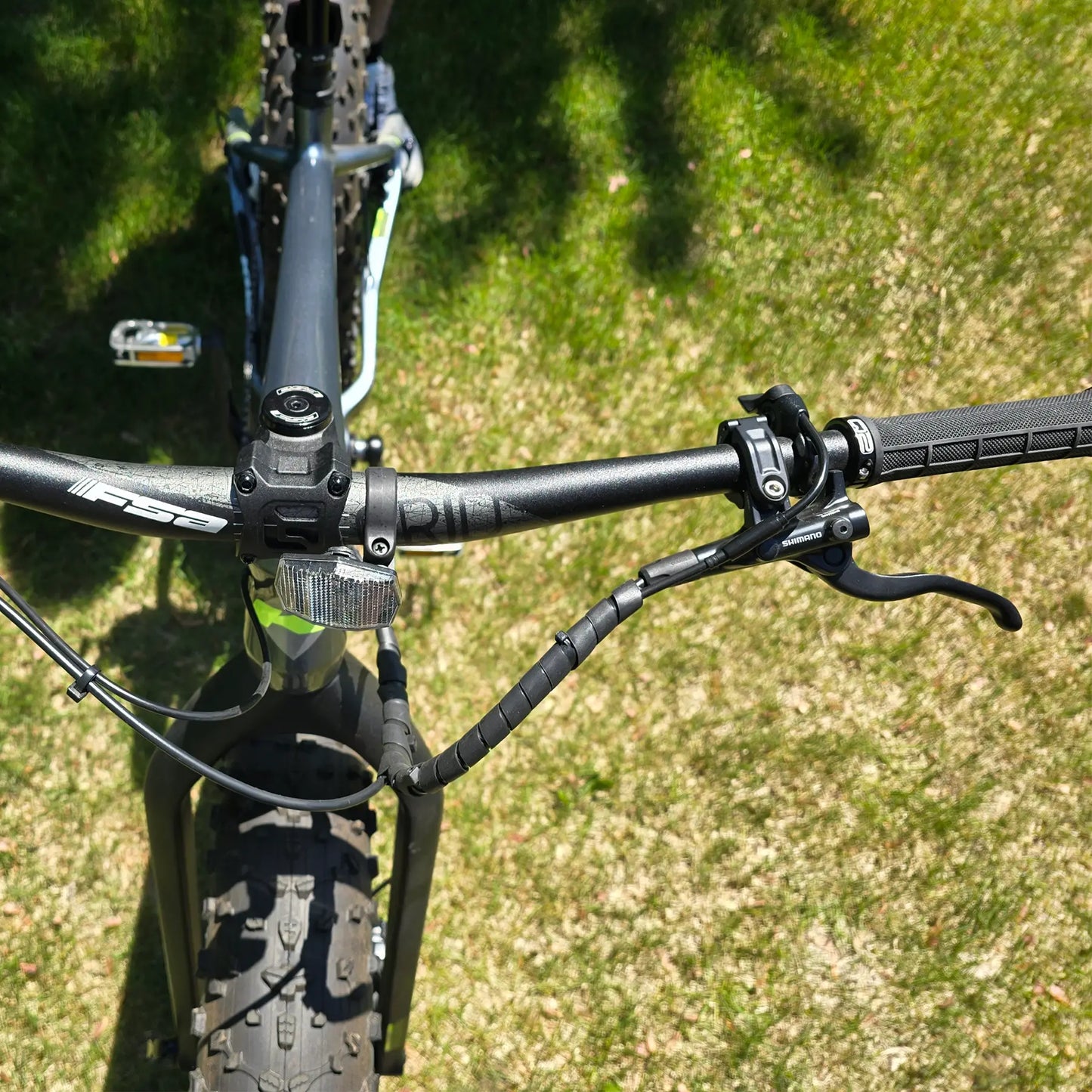 Closeup view of the handlebars on the KHS 4 Season 5000 Fat Bike with Carbon Fork in Dark Grey in an outdoor setting.