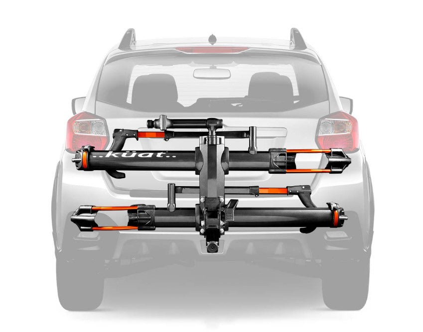 A Kuat NV 2.0 gray and orange anodized bike rack for two bikes that will fit a 2 inch receiver hitch. In this image it is mounted on a car and tilted upright for when not in use.
