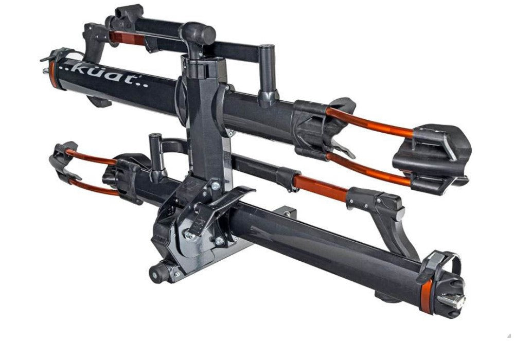 An angled view of a Kuat NV 2.0 gray and orange anodized bike rack for two bikes that will fit a 2 inch receiver hitch in an upright position.