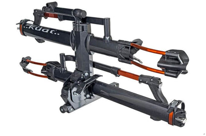An angled view of a Kuat NV 2.0 gray and orange anodized bike rack for two bikes that will fit a 2 inch receiver hitch in an upright position.