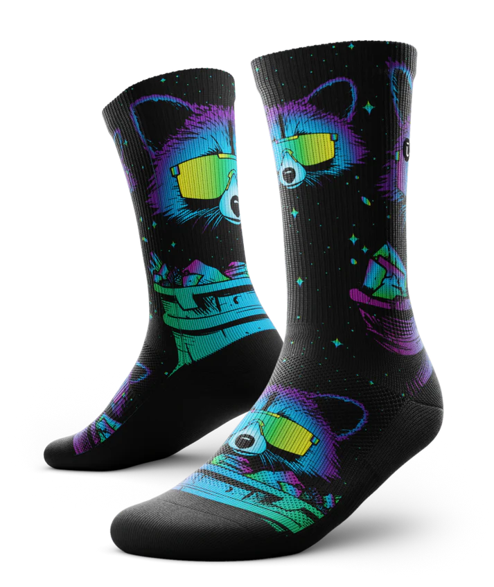 Pair of black socks printed with heads of racoons wearing yellow sunglasses and garbage cans.  Racoons and garbage cans are colored in blues, purples and teals.