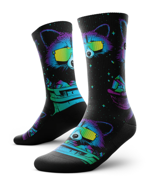 Pair of black socks printed with heads of racoons wearing yellow sunglasses and garbage cans.  Racoons and garbage cans are colored in blues, purples and teals.
