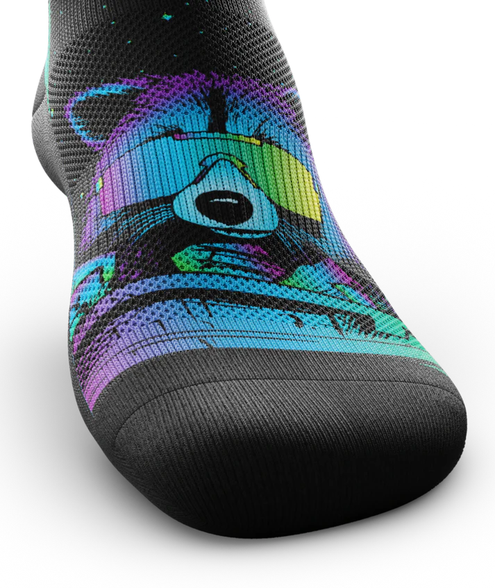 Front top of a black sock with a racoon head in blue, purple and teal wearing yellow sunglasses. 