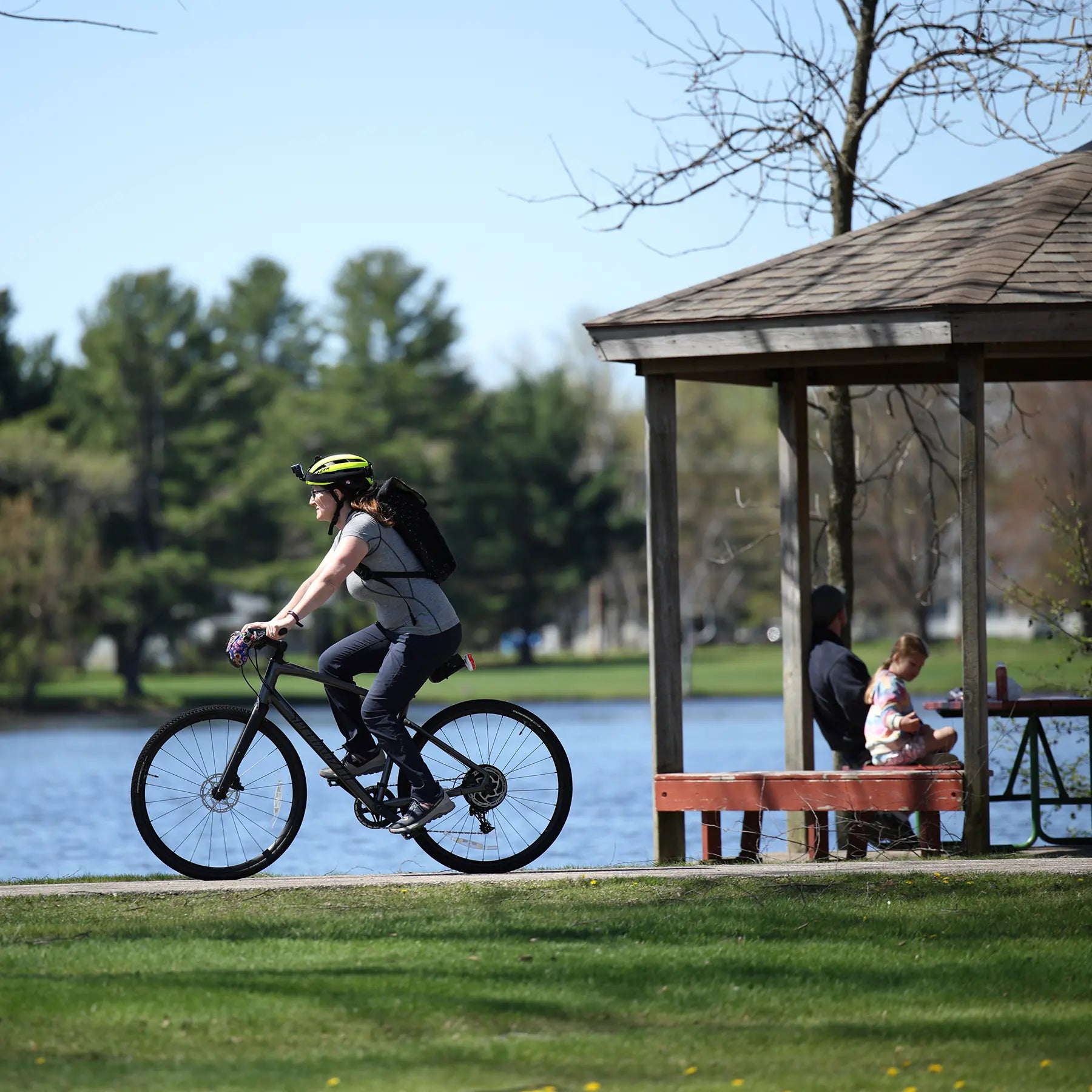 Person riding a bicycle along the Wisconsin River on the Green Circle Trail with a gazebo in the background.