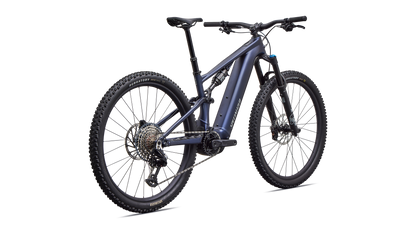 A full-suspension electric mountain bike in a dark metallic blue-gray color, featuring a black battery pack, front suspension fork, and knobby tires, shown on a solid white background.