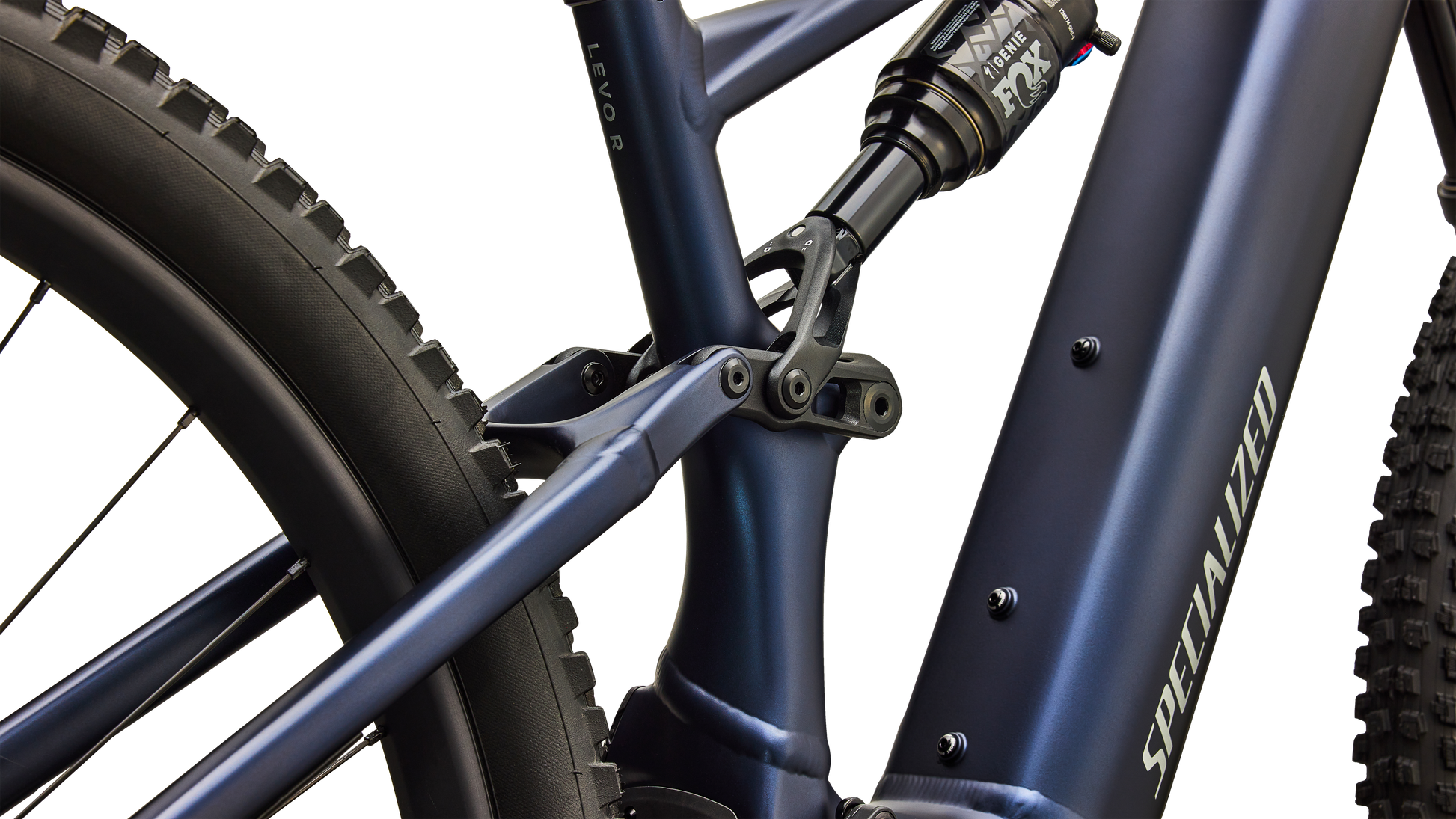 Close-up of a Specialized mountain bike frame in matte navy blue, showing the seat tube junction, rear shock, and part of the rear tire against a clean white background.