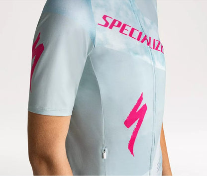  A close up right shoulder view of a person wearing a light blue Specialized Women's Foundation cycling jersey with pink Specialized logo on a white background.