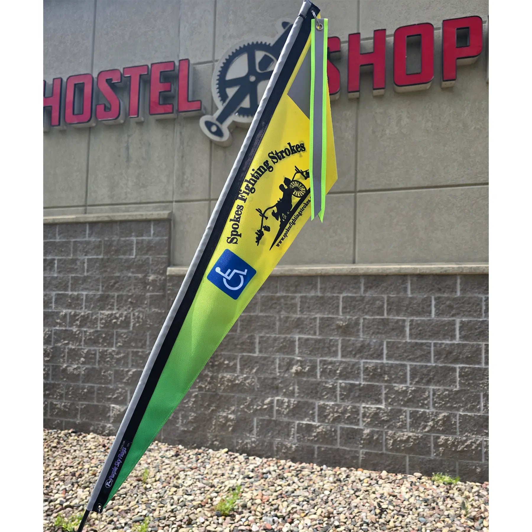 Closeup view of the Spokes Fighting Strokes Logo Flag with Handicapped Symbol in an outdoor setting.
