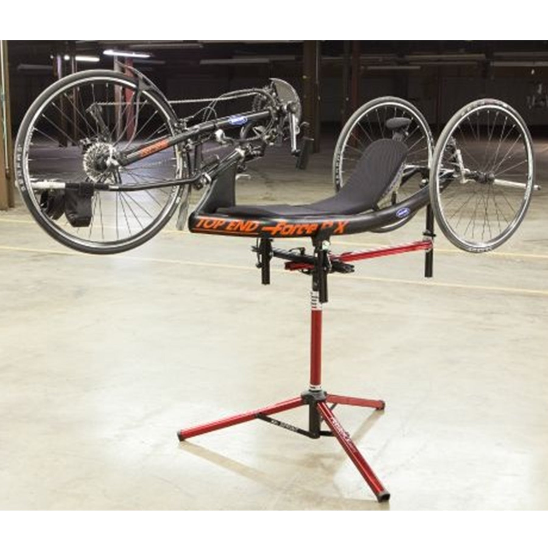 Handcycle on a red repair stand with 'Top End Force' branding in an indoor setting.