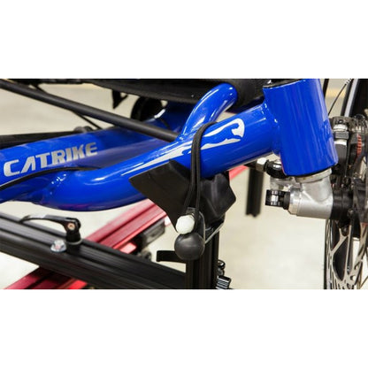 Close-up of a blue bicycle frame with 'Catrike' branding on a red repair stand against a white background.