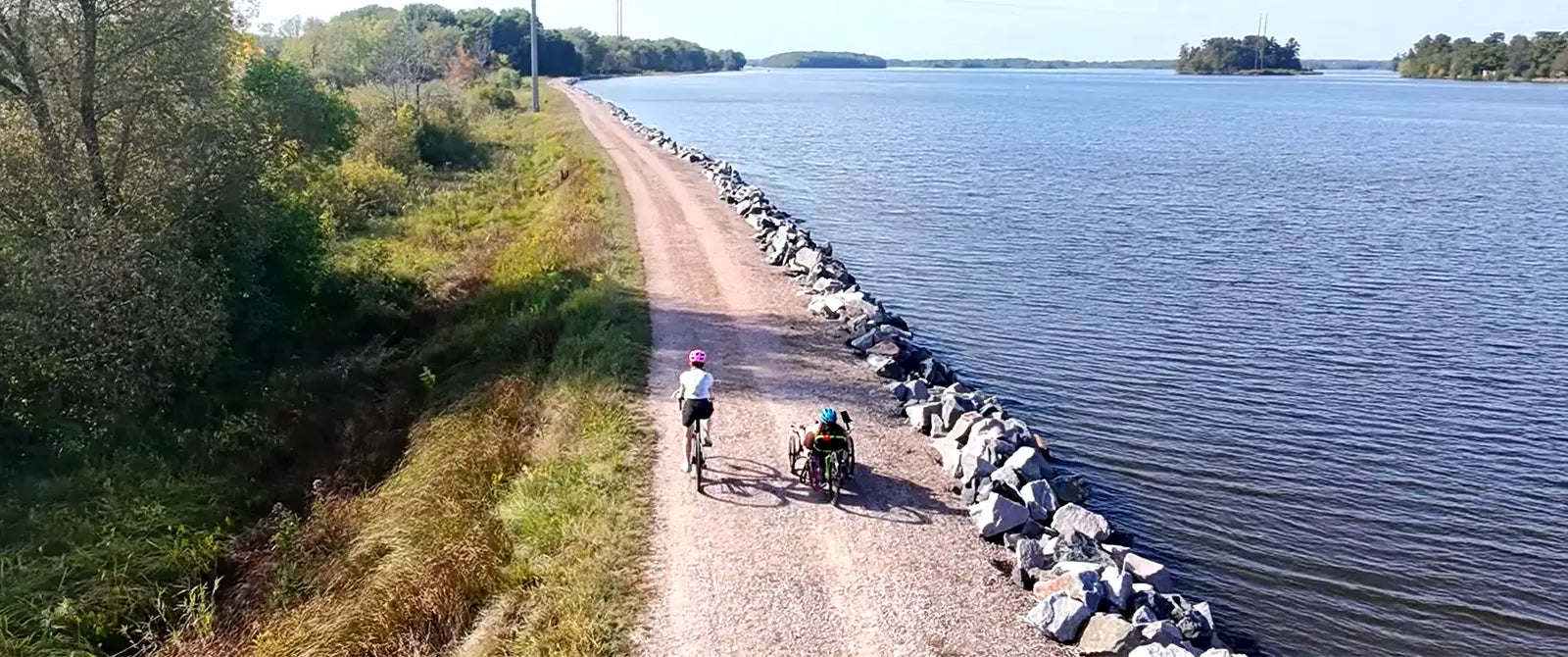 A biker and a triker ride along a gravel path along the Wisconsin River.