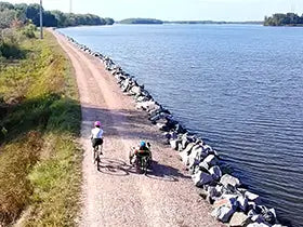 A biker and a triker ride along a gravel path along the Wisconsin River.