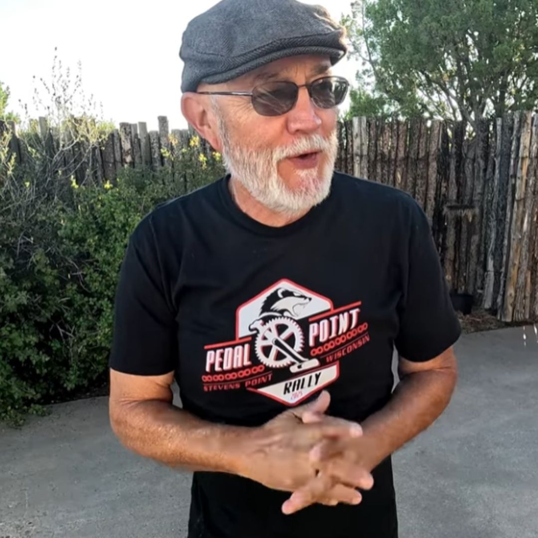 Man wearing a black t-shirt, with a Catrike logo and text about the Pedal Point Rally, is standing outdoors.
