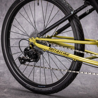 Closeup view of the rear wheel and drivetrain on the TerraTrike E.V.O. Proton Green Recumbent Trike against a gray background.