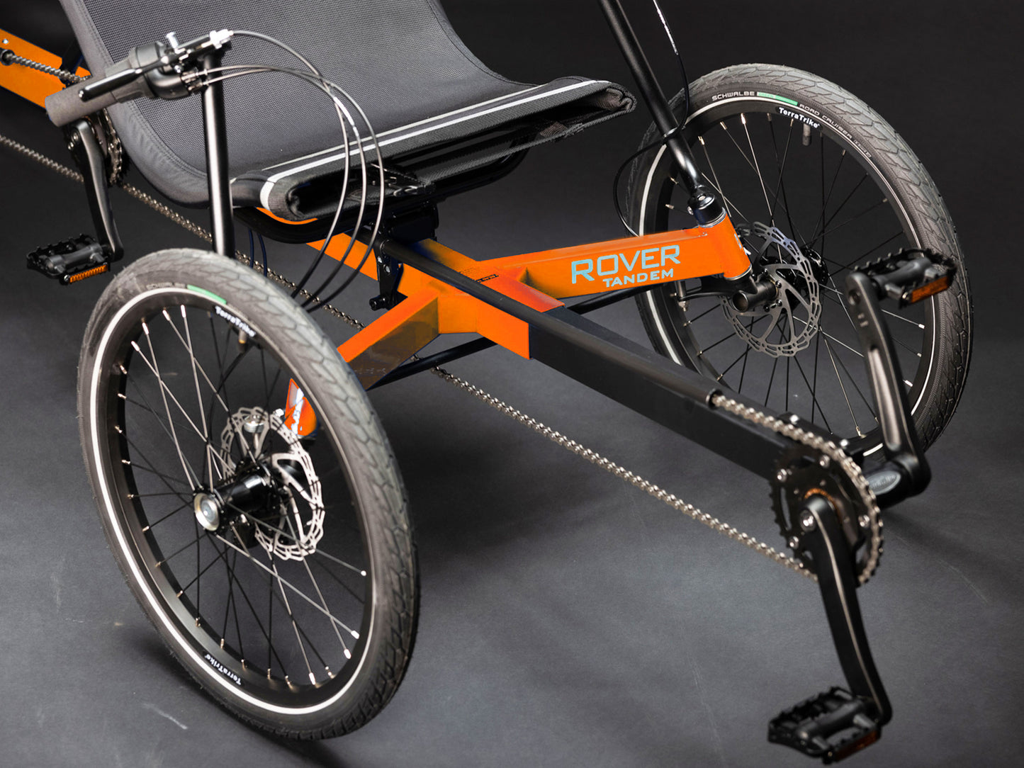 Closeup front view of the TerraTrike Rover Tandem Recumbent Trike in Habanero Orange against a grey background.