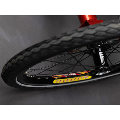 Closeup view of a front wheel on the TerraTrike Tandem Pro Sparkle Copper Recumbent Trike against a grey background.