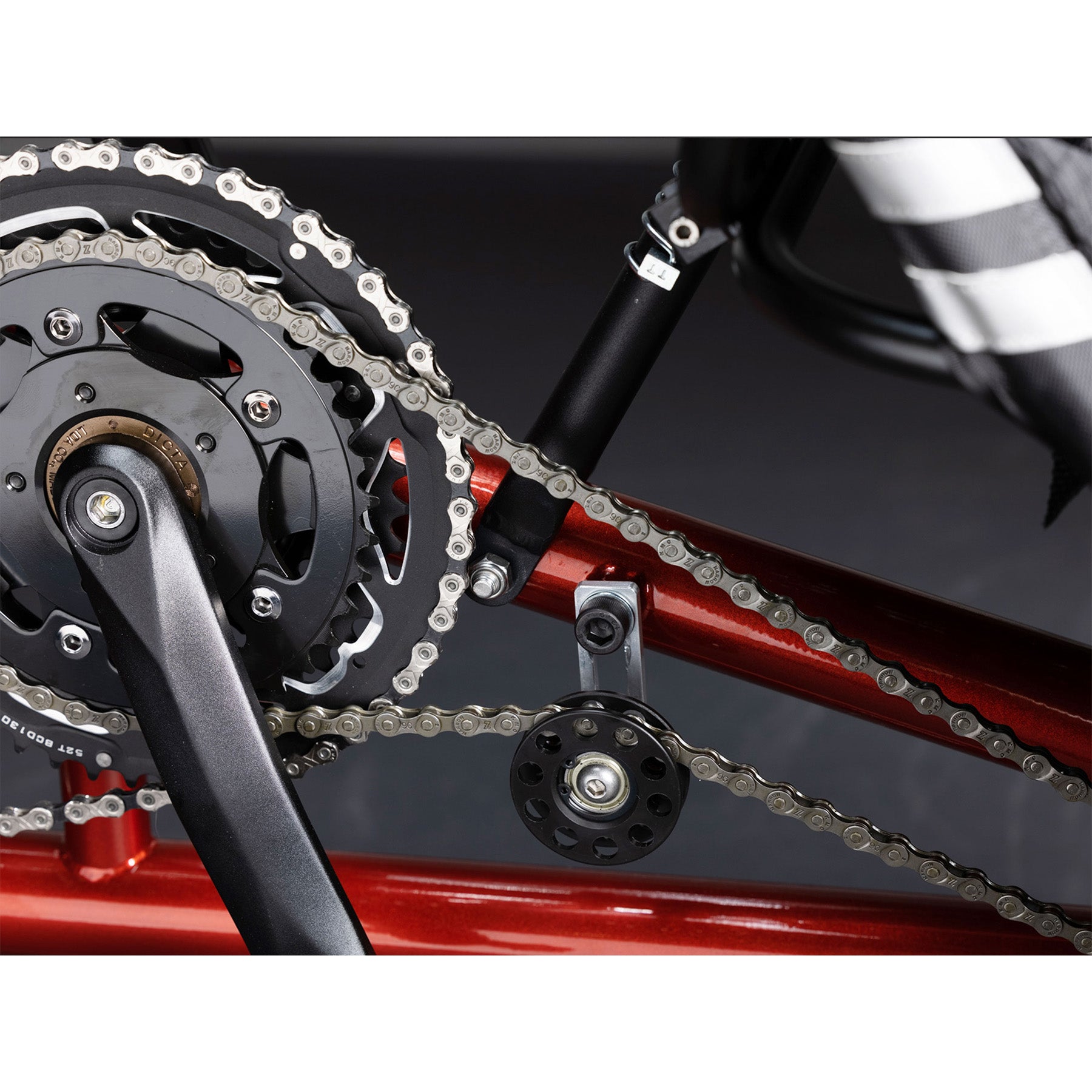 Closeup view of the crankset and idler on the TerraTrike Tandem Pro Sparkle Copper Recumbent Trike against a grey background.