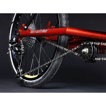 Closeup view of the rear wheel and idler on the TerraTrike Tandem Pro Sparkle Copper Recumbent Trike against a grey background.