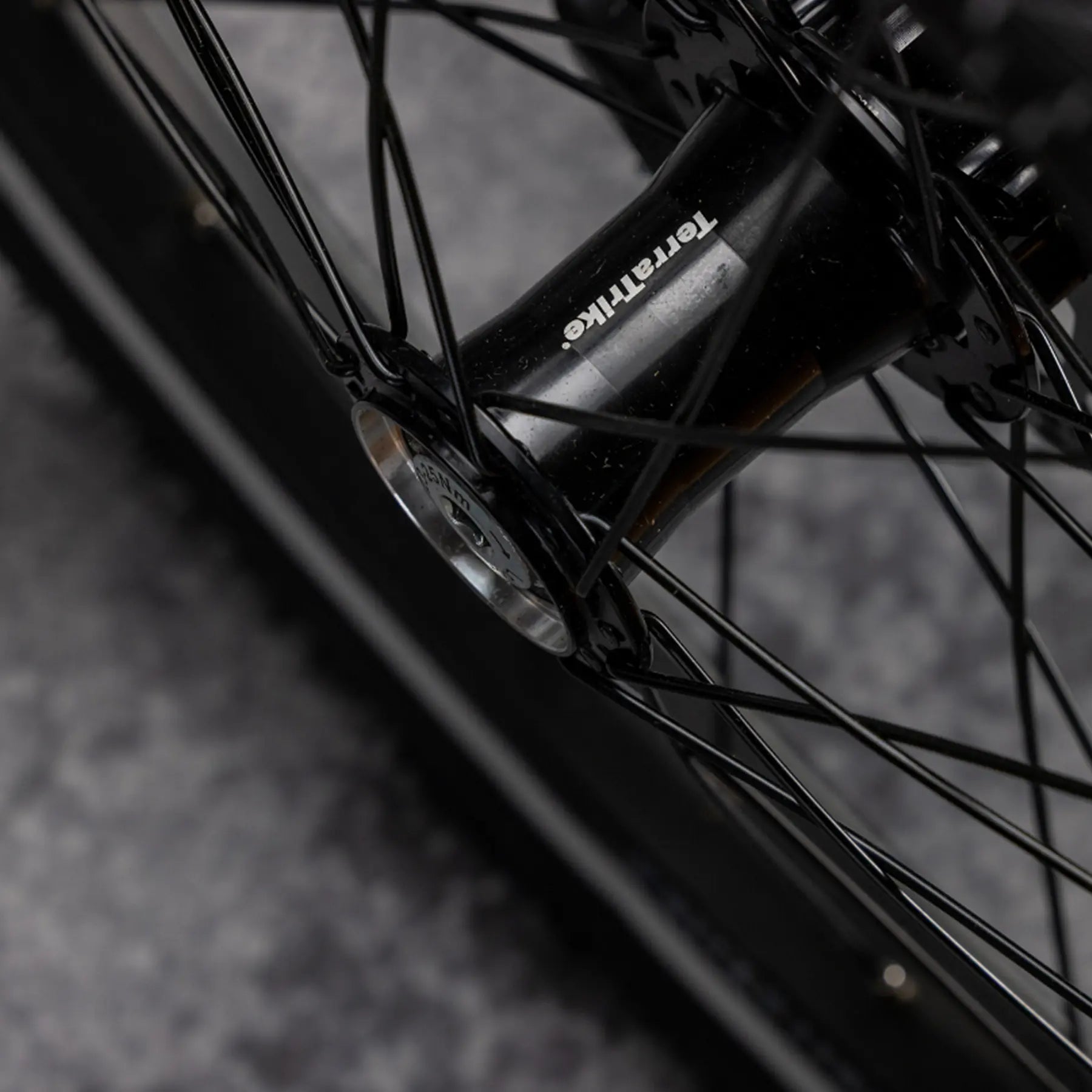 Closeup view of the TerraTrike front hub on the TerraTrike Traveler Champagne Recumbent Trike against a gray background.