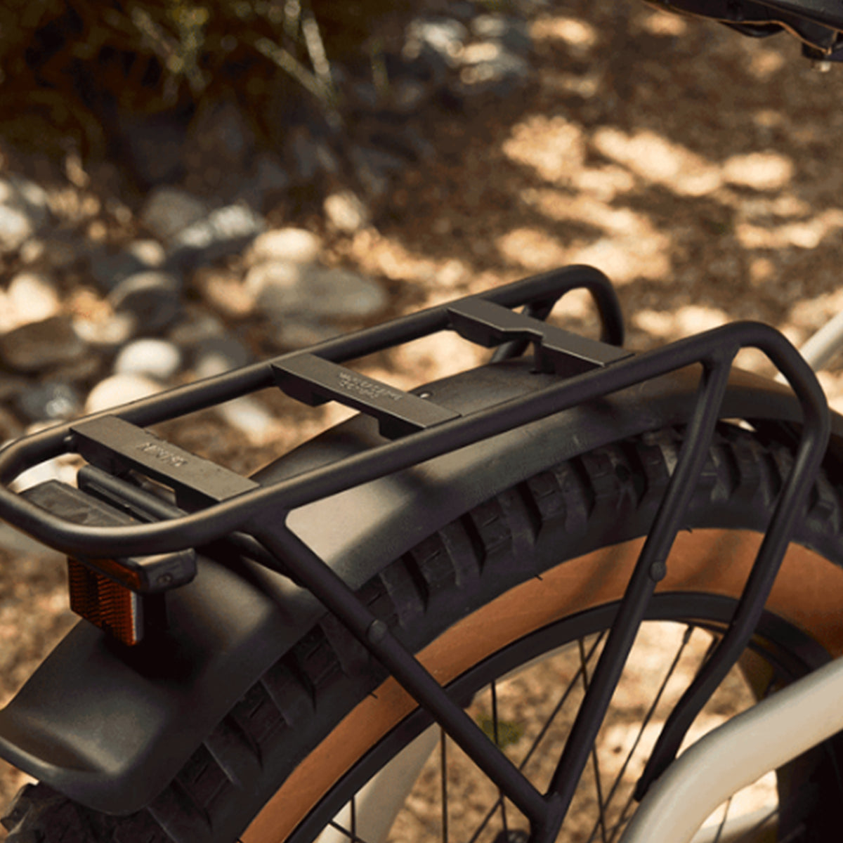 Closeup view of the taillight, fender and rear rack on the Trek Borrego+ S against a blurred out outdoor background.