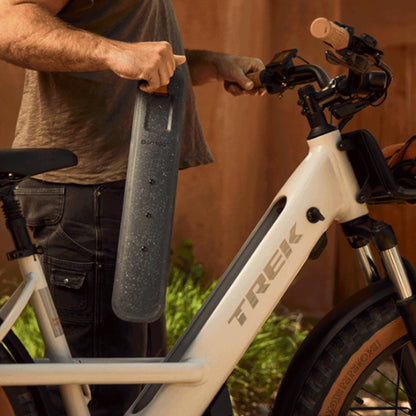Closeup view of a man holding the battery for the Trek Borrego+ S in Matte Buff Beige in an outdoor setting.