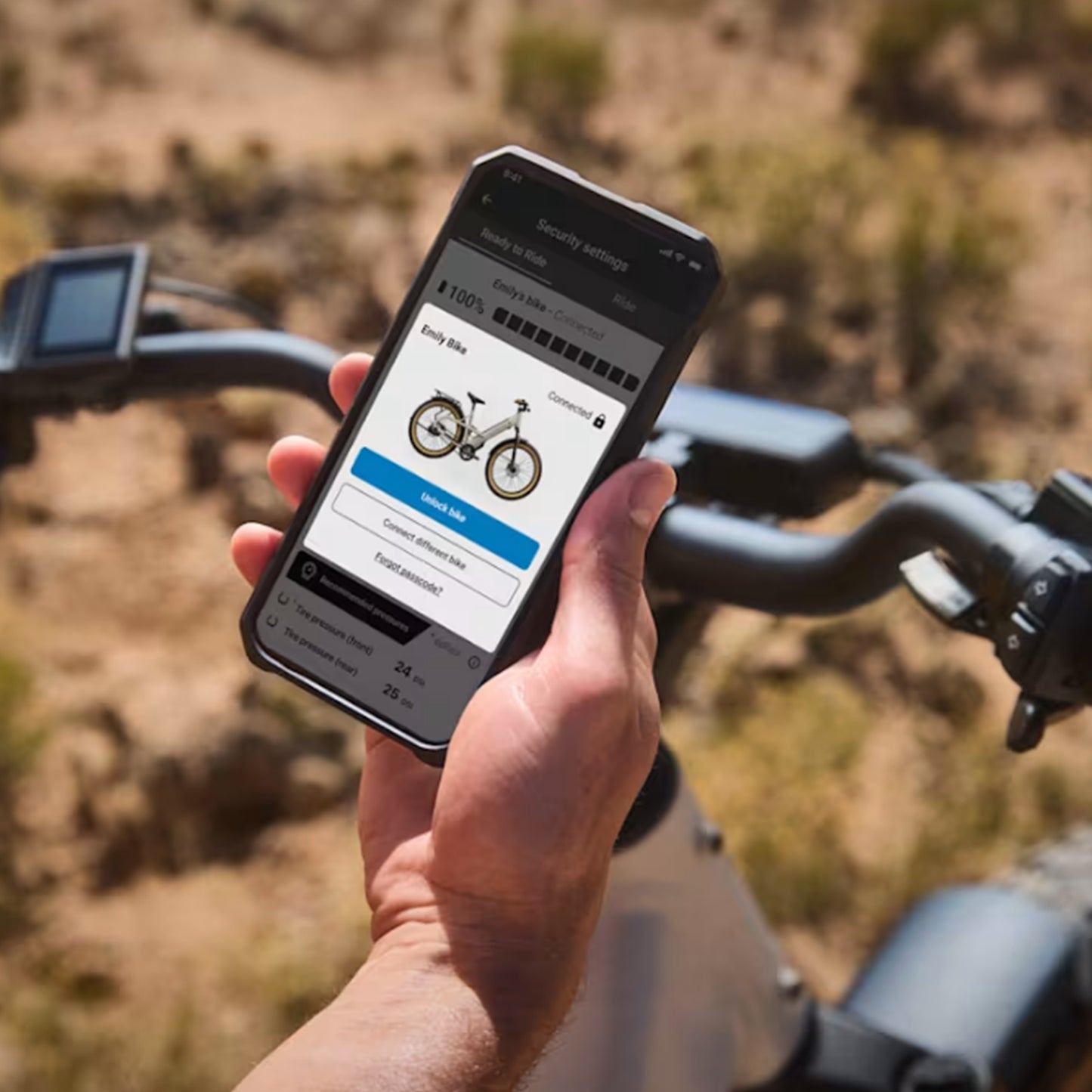 Image of a person holding a cell phone with the Trek Central App on it fo0r fine tuning control of the Trek Borrego+ S against an outdoor setting.