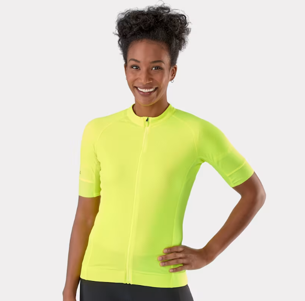 A woman wearing a bright neon yellow short-sleeve Trek Circuit cycling jersey with a full front zipper, posing against a light gray studio background.