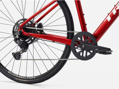 Close-up of a red Trek FX bicycle's rear wheel and gear system on a white background
