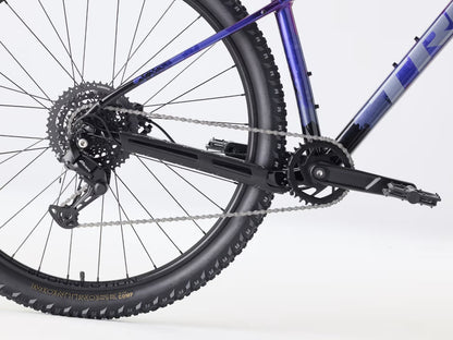 Close-up of a purple Trek Marlin 4 bicycle wheel and chain on a white background.