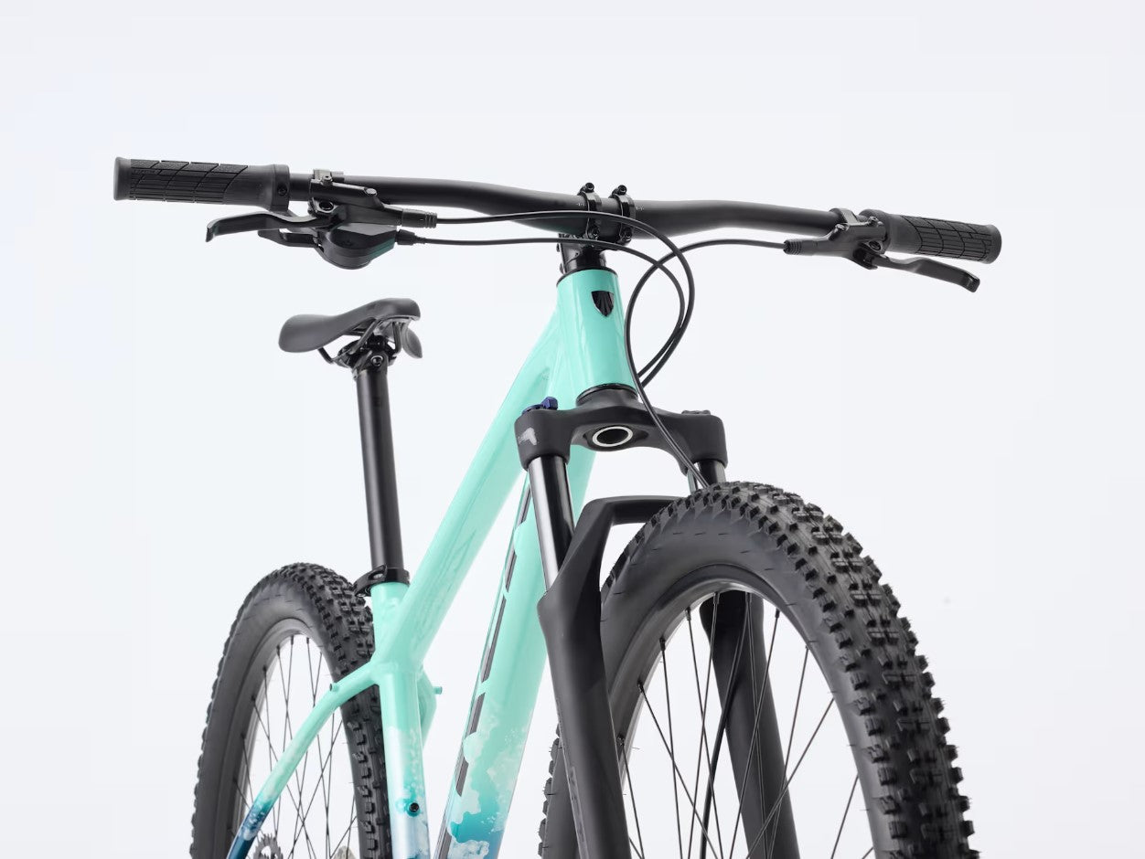 A close up front view of a seafoam green Trek Marlin 5 bicycle with black components on a light gray background