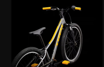 Grey Trek Precaliber bicycle with orange accents on a black background.