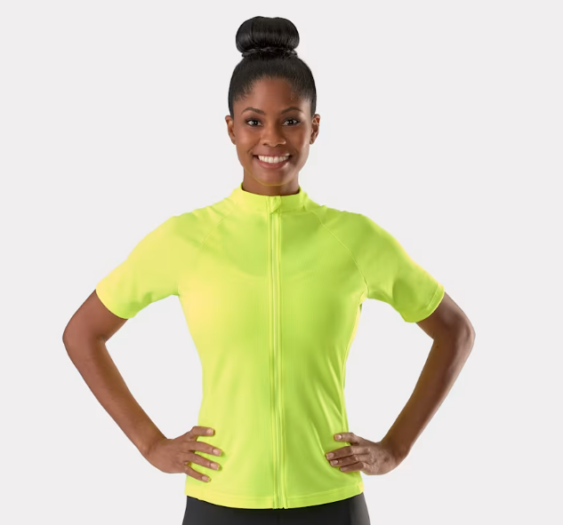 A woman wearing a Radioactive yellow Trek Solstice short-sleeve zip-up athletic top against a light gray studio background.