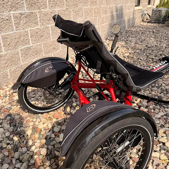 Rear closeup view of the Hase Used Kettwiesel Full Suspension Red Recumbent Trike in an outdoor setting.