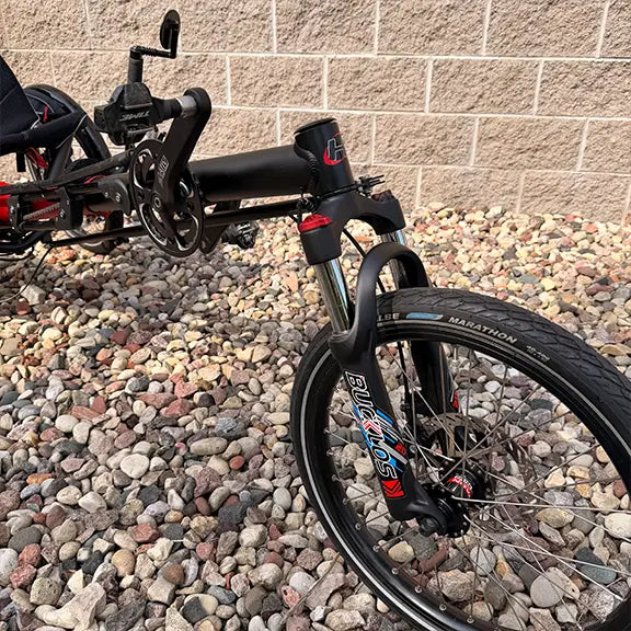 Front closeup view of the Hase Used Kettwiesel Full Suspension Red Recumbent Trike in an outdoor setting.
