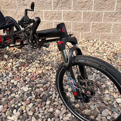 Front closeup view of the Hase Used Kettwiesel Full Suspension Red Recumbent Trike in an outdoor setting.