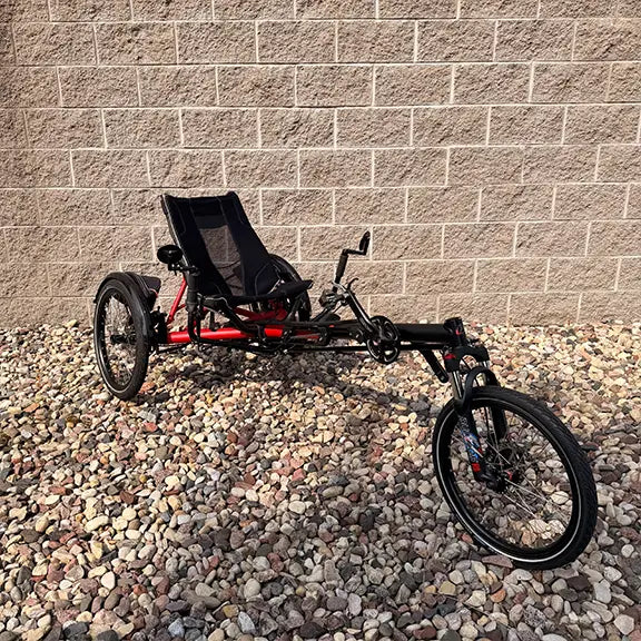 Angled front view of the Hase Used Kettwiesel Full Suspension Red Recumbent Trike in an outdoor setting.