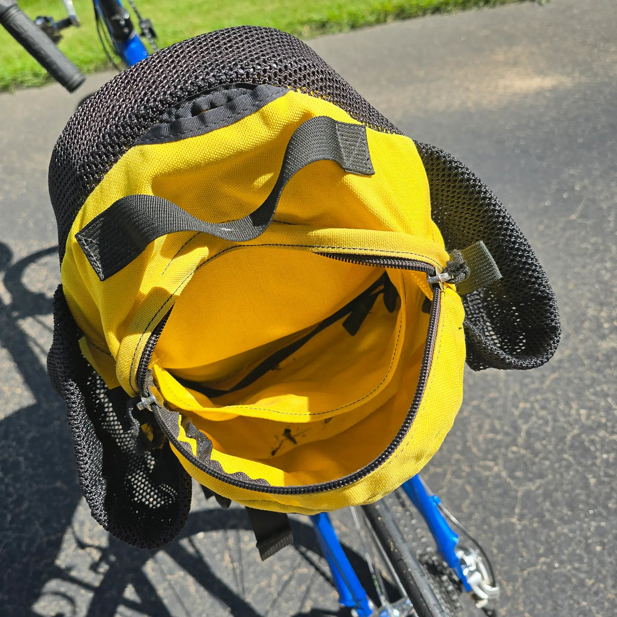 Closeup view of the inside of the yellow Hostel Shoppe seat bag on the Used Club Dual 650c Blue Small Recumbent Bike in an outdoor setting.