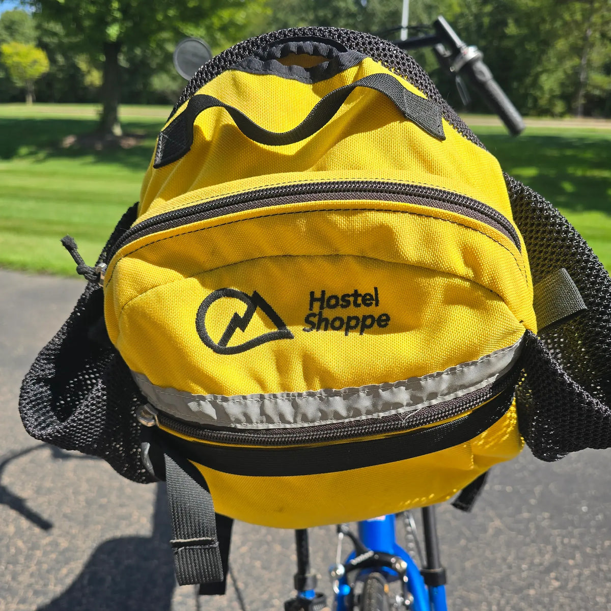 Closeup view of the yellow Hostel Shoppe seat bag on the Used Club Dual 650c Blue Small Recumbent Bike in an outdoor setting.