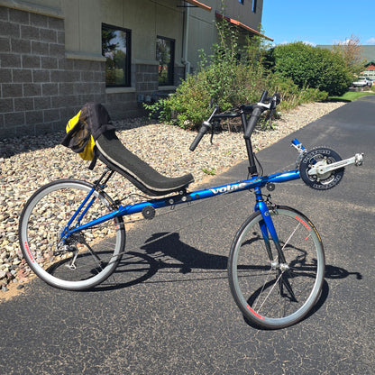 Side view of the Volae Used Club Dual 650c Blue Small Recumbent Bike in an outdoor setting.