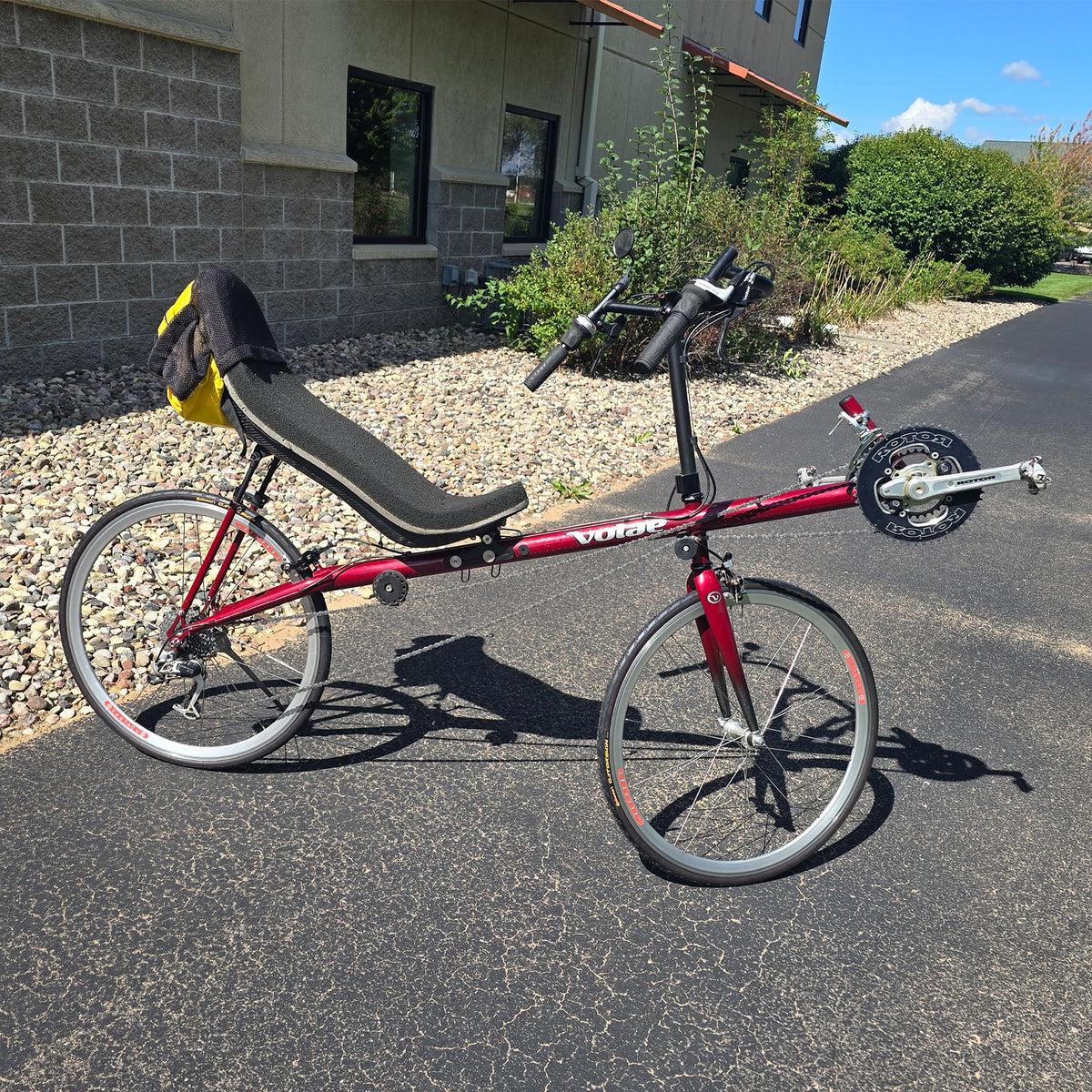 Side view of the Volae Used Club Dual 650c Red Large Recumbent Bike in an outdoor setting.