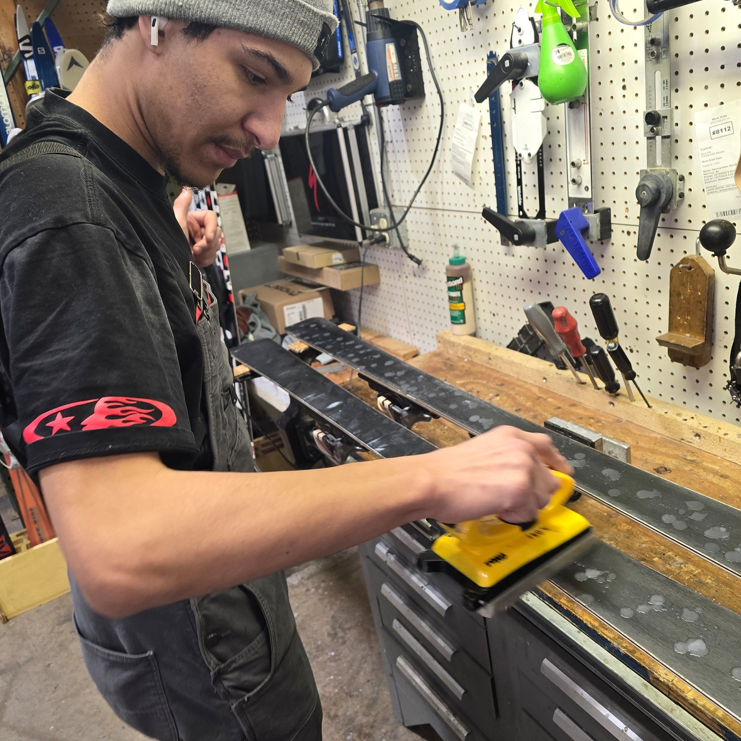Person waxing a set of skis in a workshop.