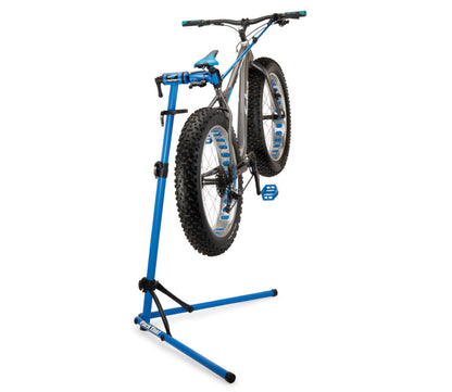 Studio image of repair stand in use with a silver fat tire bicycle mounted in the clamp.