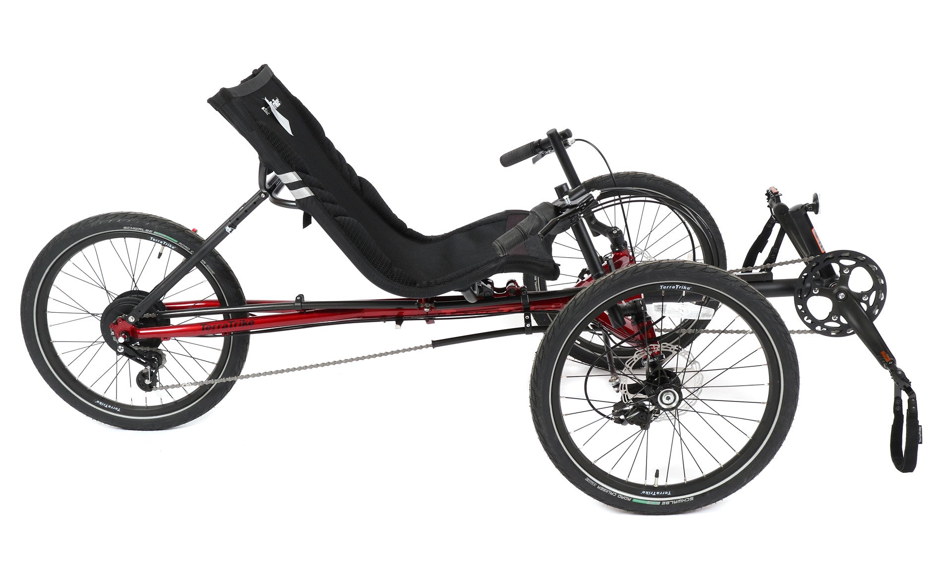 Side view of a red and black TerraTrike Traveler recumbent trike with a black seat and folding handlebars, equipped with a chain drive and mechanical disc brakes.